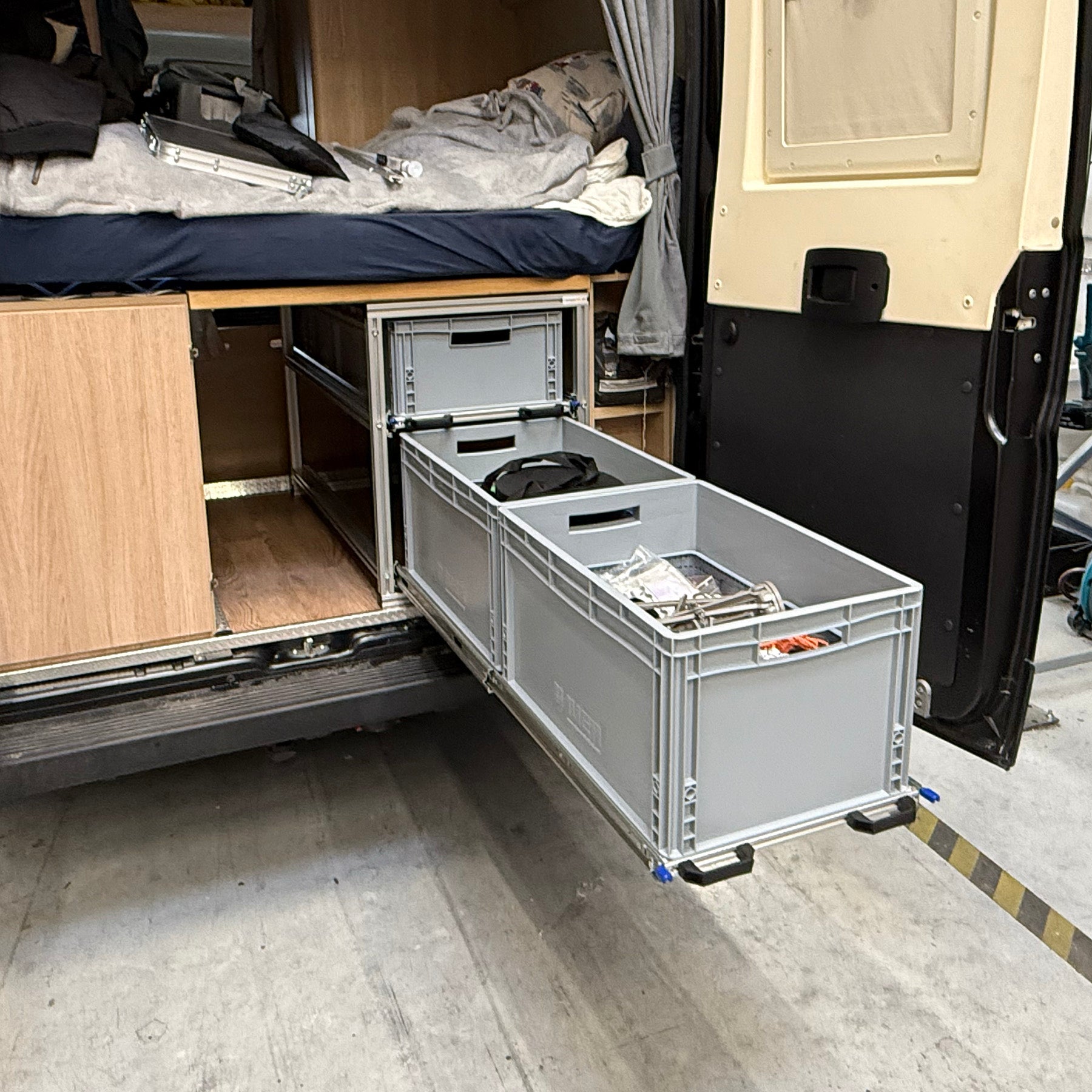 Ausziehbares Regalsystem im Fahrzeugheck mit zwei Ebenen für Euroboxen, unterstützt durch belastbare Verriegelungsauszüge.